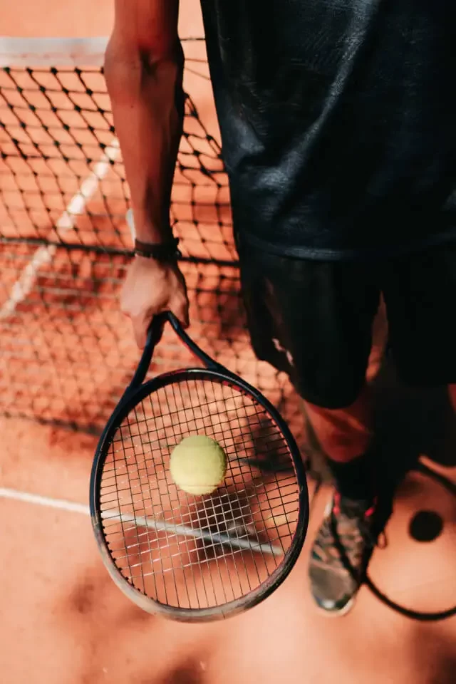 Tennis player on the court holding racket and a ball