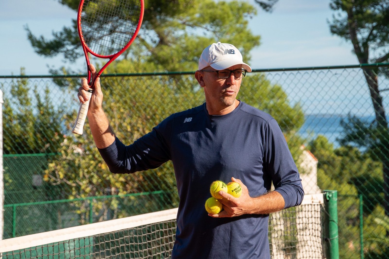 Tennis coach on the court with racket and a balls